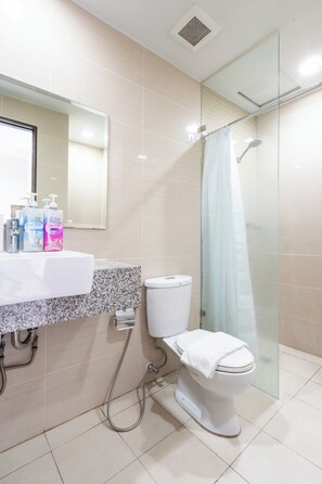A bathroom with a toilet, a shower, and a sink with soap dispensers. - The Florence Venice Mall Modern 1BR w/Balcony View (Taguig)