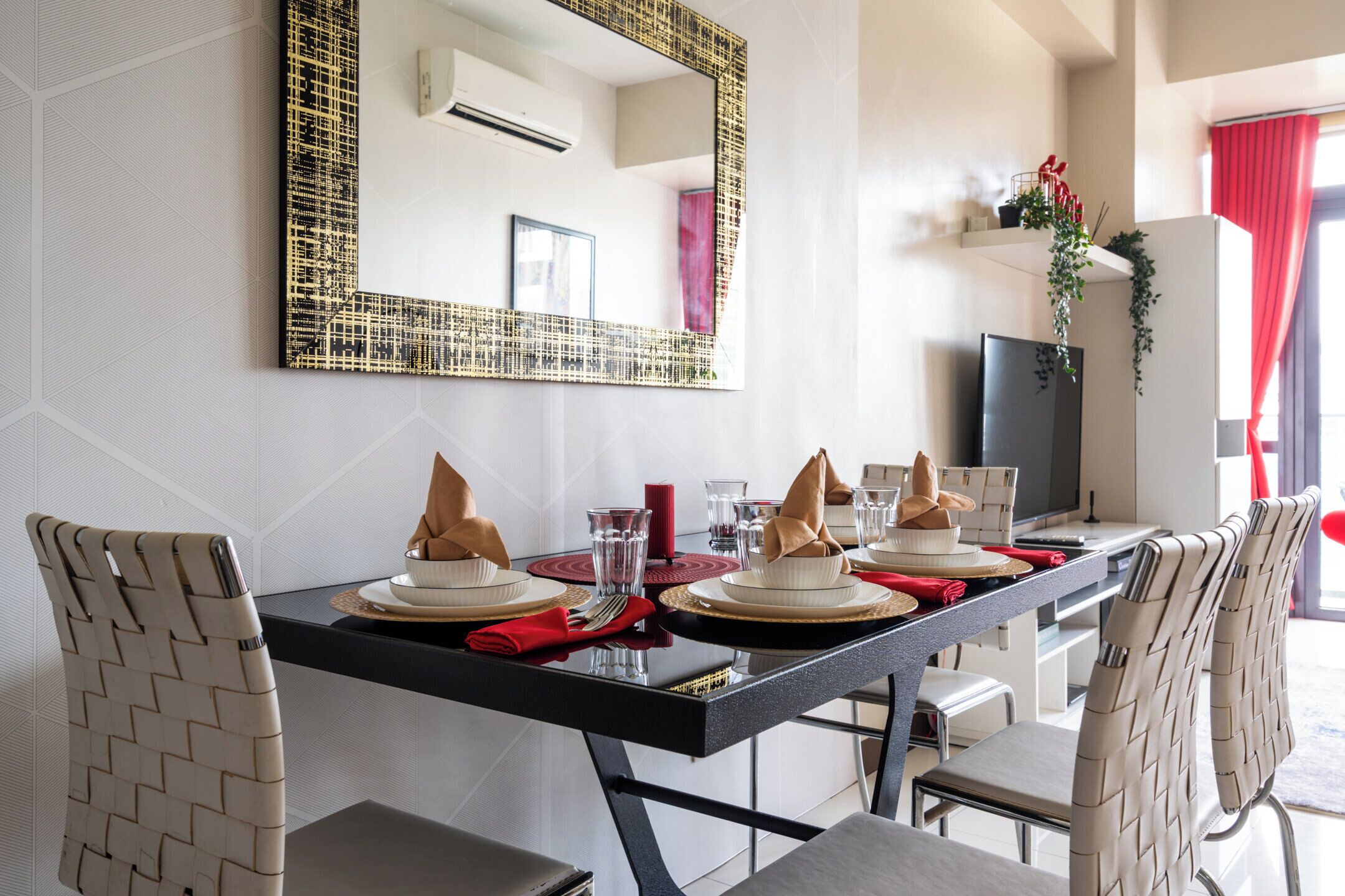 A dining area with a black table, white chairs, and a large mirror on the wall.