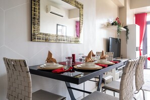 A dining area with a black table, white chairs, and a large mirror on the wall. - The Florence Venice Mall Modern 1BR w/Balcony View (Taguig)