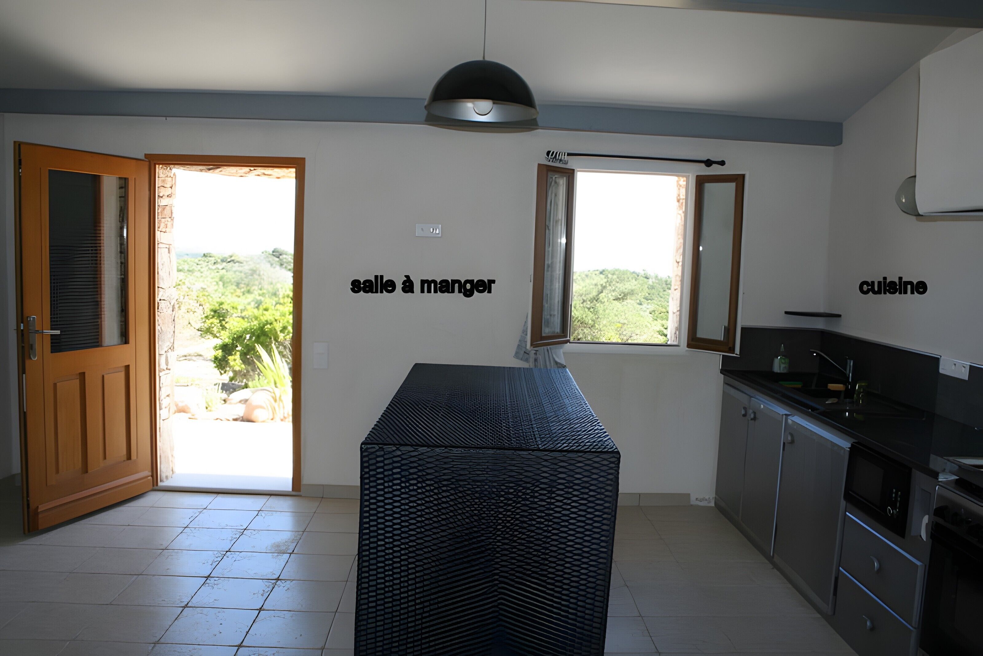 A kitchen with a built-in island, a window, and a door leading to a balcony.