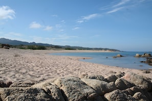 Een strand met een rotsachtige voorgrond en een heldere lucht.