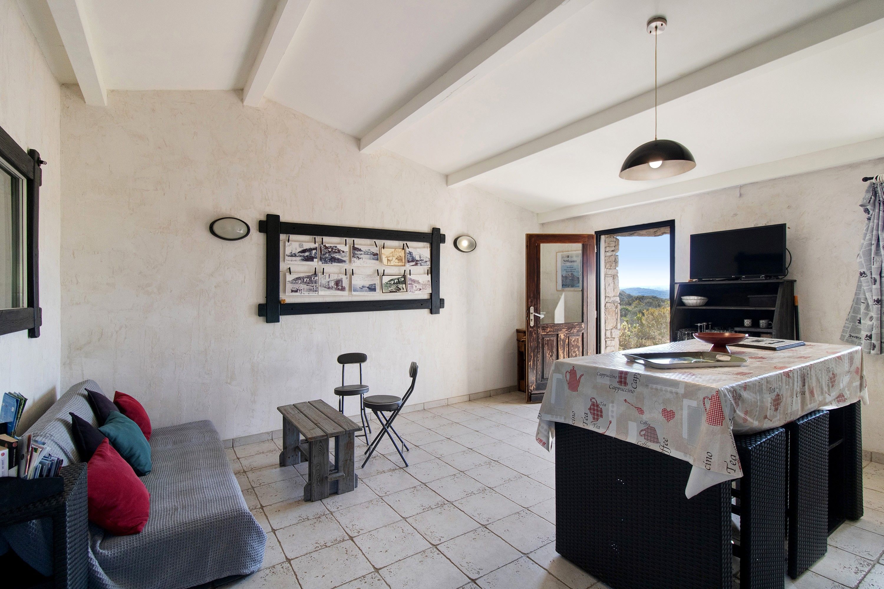 A cozy living room with a sofa, a small table, and a kitchen area with a table set for dining.