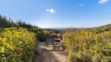 Un cadre naturel en plein air offrant une vue dégagée sur l’horizon, un espace de repos avec une chaise et une table, et un sentier de terre.