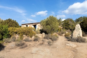 A rustic stone building with a tiled roof, surrounded by dry vegetation and a clear sky. - Holiday Home 'La Bergerie' with Sea View, Wi-Fi and Air Conditioning (Bonifacio)