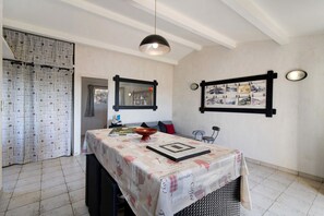 A dining area with a table set for two, a hanging light fixture, and a wall-mounted mirror. - Holiday Home 'La Bergerie' with Sea View, Wi-Fi and Air Conditioning (Bonifacio)