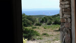 A view through a window with a stone wall, overlooking a coastal landscape with greenery and sailboats on the sea. - Holiday Home 'La Bergerie' with Sea View, Wi-Fi and Air Conditioning (Bonifacio)
