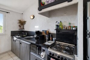 A kitchen with a gas stove, a coffee maker, and various kitchen utensils. - Holiday Home 'La Bergerie' with Sea View, Wi-Fi and Air Conditioning (Bonifacio)
