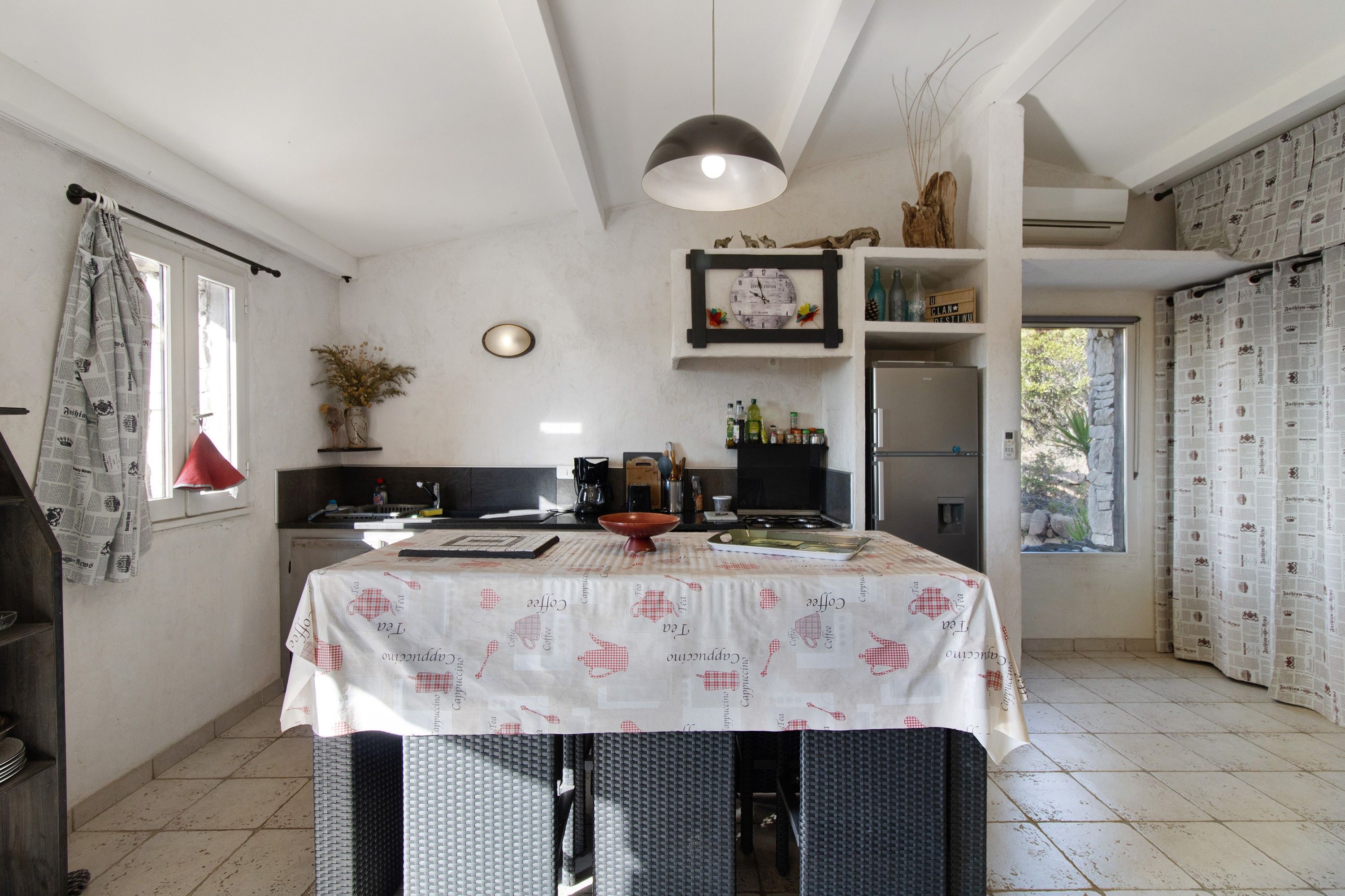 A kitchen with a dining table, a clock, and a refrigerator.