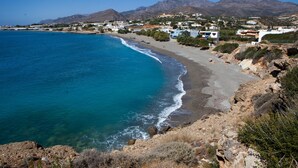 A coastal town with a beach, houses, and mountains in the background. - Apartment 'Porto Beach' with Sea View, Wi-Fi and Air Conditioning (Makry Gialos)