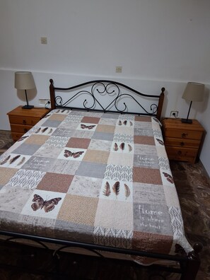 Una cama con colcha adornada con motivos de mariposas y la frase 'Home is where the heart is'.