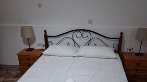 A neatly made bed with white linens and rolled towels, two bedside tables with lamps, and a marble floor. - Apartment 'Porto Beach' with Sea View, Wi-Fi and Air Conditioning (Makry Gialos)