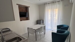 A modern kitchen with a built-in oven, a dining area with a table and chairs, and a seating area with a blue chair.