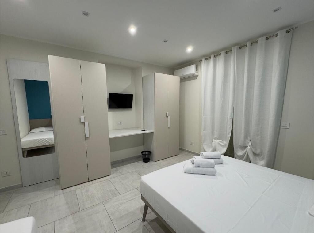 Ein modernes Schlafzimmer mit Bett, Kleiderschrank und Fernseher.