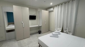 Ein modernes Schlafzimmer mit Bett, Kleiderschrank und Fernseher.