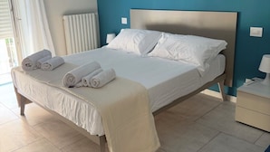 Ein Hotelzimmer mit Bett, Nachttisch, Lampe und Blick ins Freie.