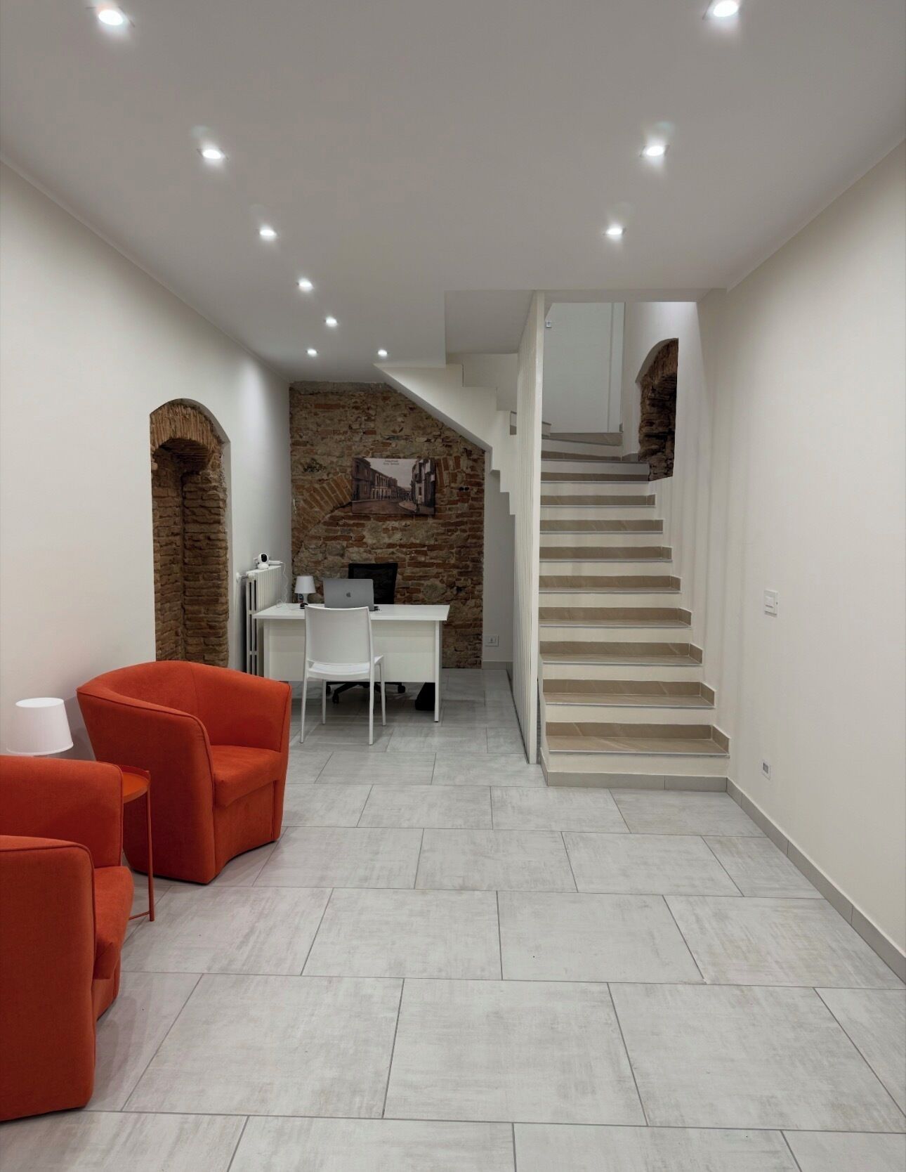 Un intérieur moderne avec un escalier, un mur en pierre et un espace bureau.