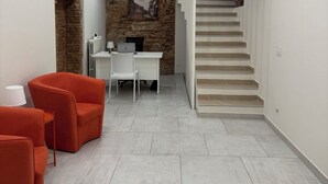 A modern interior with a staircase, a stone wall, and a desk area.