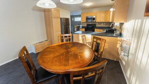 Cocina compacta con armarios de madera, una isla central y una mesa de comedor con sillas.