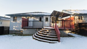 Una casa residencial con un porche delantero, una escalera que conduce a la entrada y un patio cubierto de nieve.