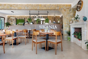 A restaurant interior with stone walls, wooden tables and chairs, a bar area, and a fireplace. - Solerata Room – Sikania Agrirelais, Mountain View (Caccamo)