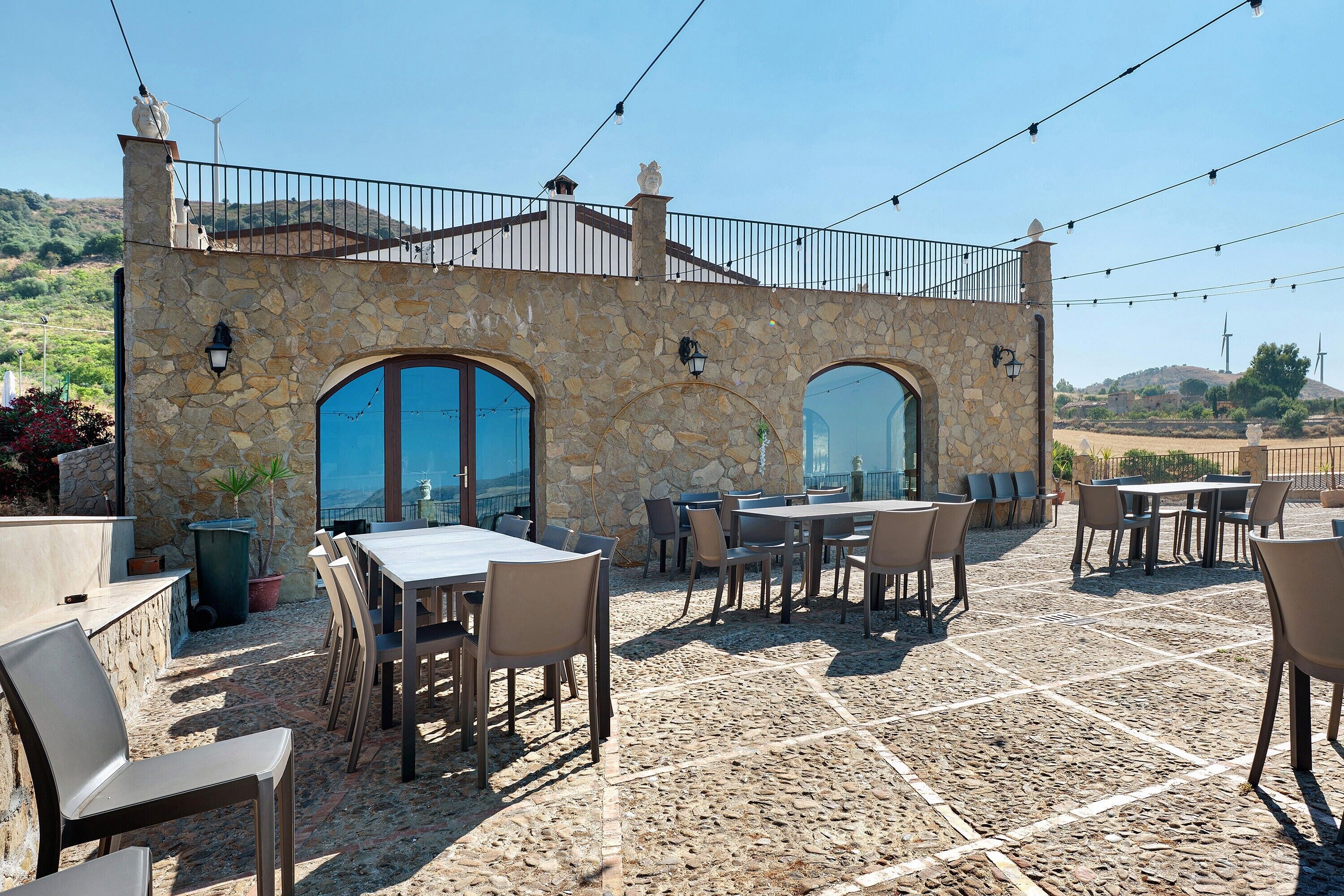 An outdoor patio with stone walls, tables, and chairs.