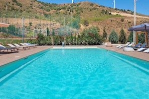 Una piscina blava i nítida amb gandules i vista a un paisatge amb muntanyes.