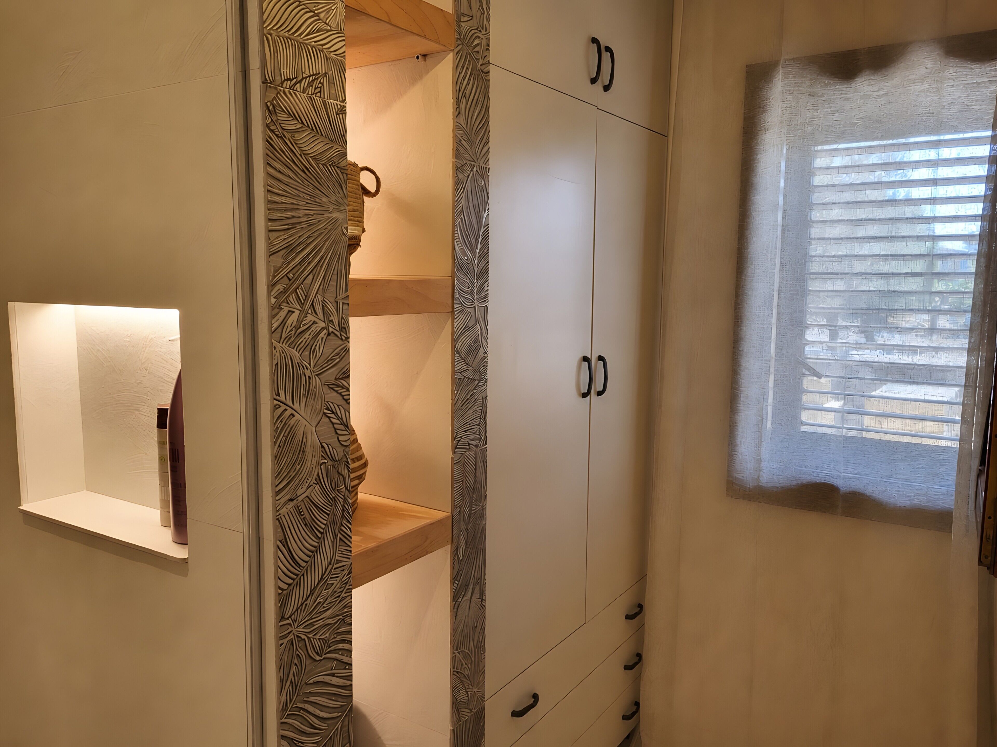 A room with a wardrobe, a shelf with items, and a window with blinds.