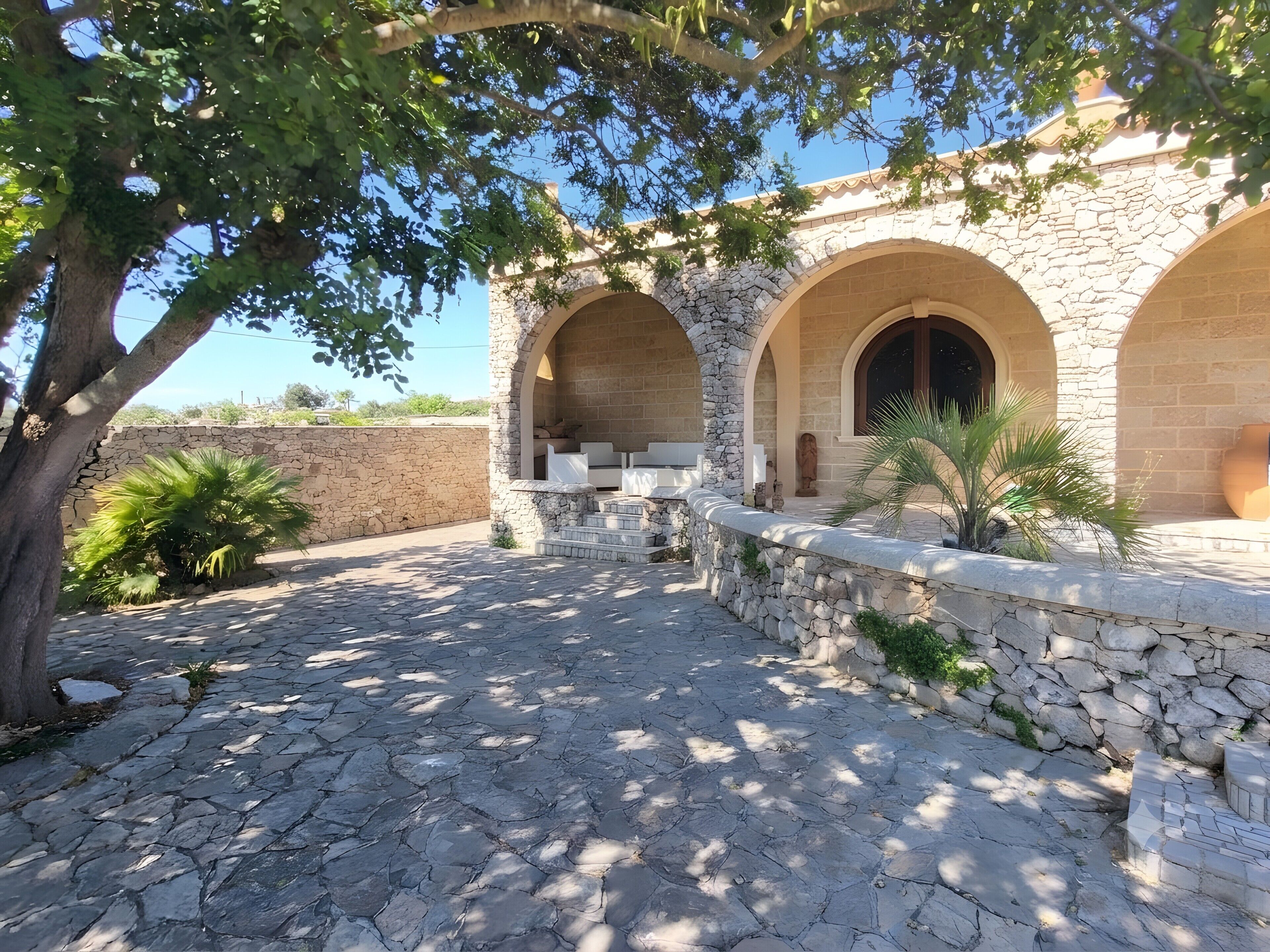 A courtyard with stone walls, arched doorways, and a paved walkway.