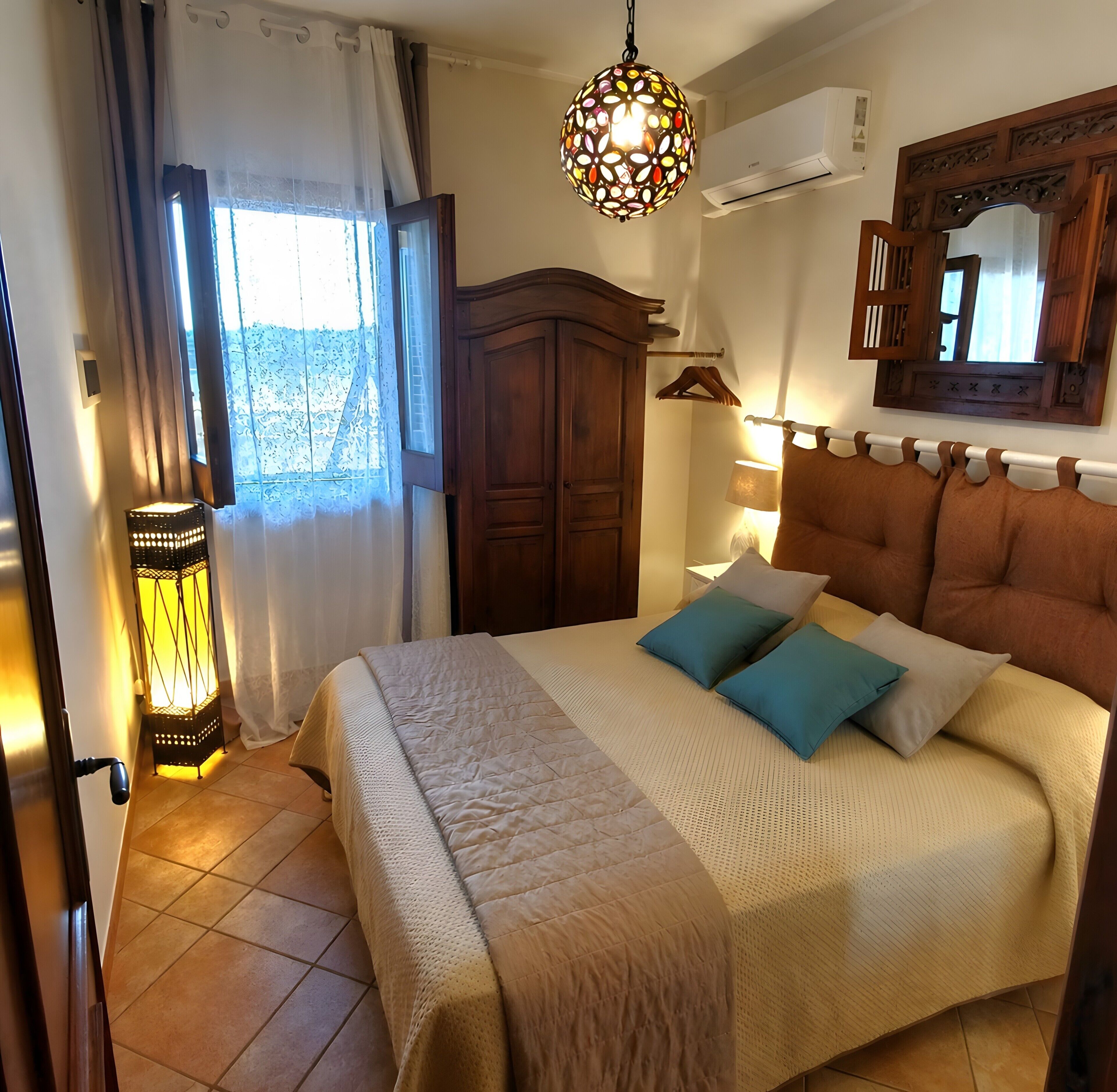 Una camera da letto con un letto, un lampadario, un armadio e una finestra con tende.