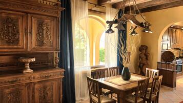 A dining area with a wooden table, chairs, and a chandelier.