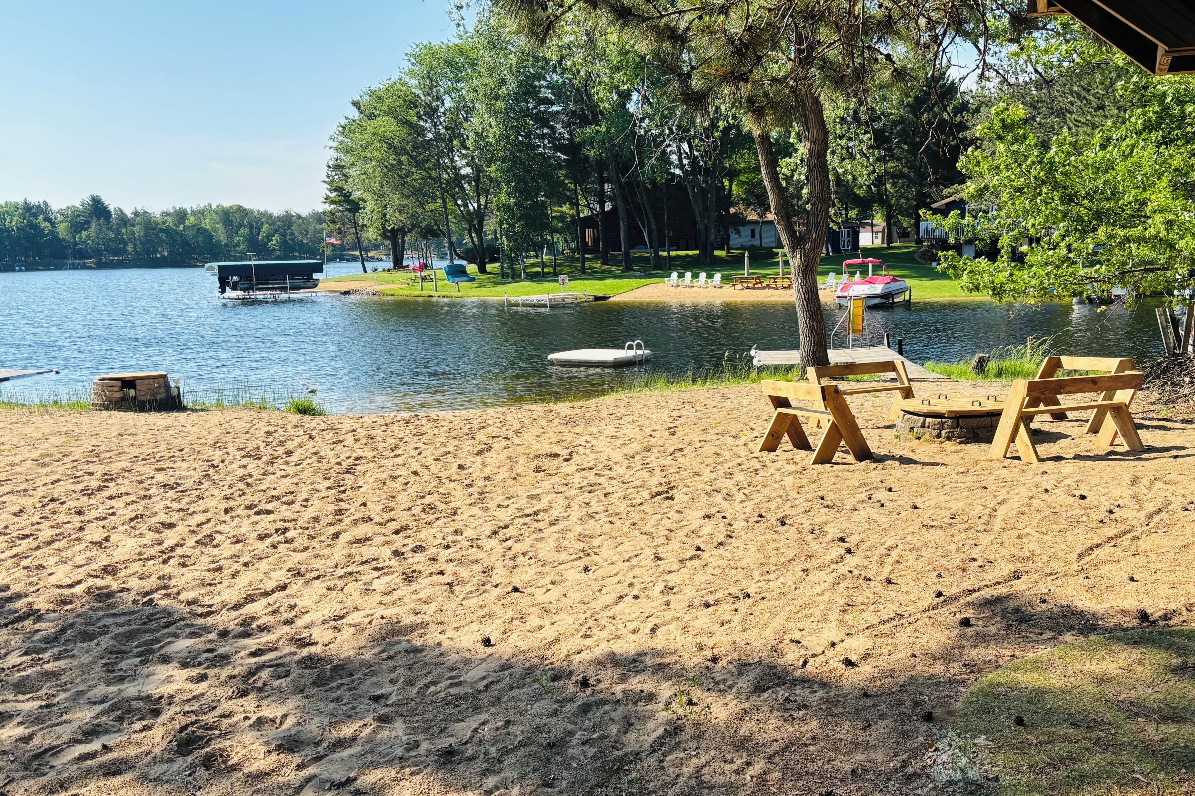 A lakeside beach with a sandy shore, a dock, and a row of beach chairs.
