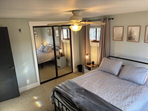 A bedroom with a bed, bedside tables, a ceiling fan, and a mirror. - 5-bedroom lake house with beautiful private beach (Nekoosa)