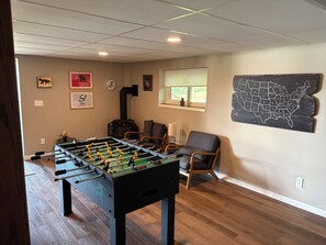 A room with a foosball table, a chair, a window with blinds, and a wall map. - 5-bedroom lake house with beautiful private beach (Nekoosa)