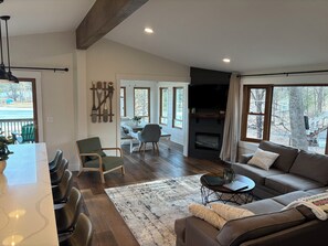 A spacious living area with a fireplace, a dining table, and a sofa. - 5-bedroom lake house with beautiful private beach (Nekoosa)