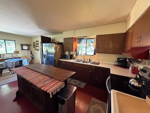 Une cuisine dotée d’un îlot central, de meubles en bois, d’un réfrigérateur, d’un four à micro-ondes et d’une cuisinière.