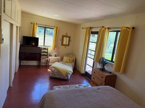 Une chambre à coucher comprenant un lit, un bureau avec une télévision, une chaise, une table de chevet avec une lampe et une commode.
