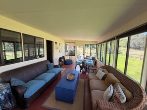 A covered patio area with a sofa, a table, and chairs. - Beautiful 3-Bedroom Home in Sonoita Under the Oaks (Sonoita)