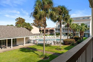 A hotel with a pool, palm trees, and a covered patio area. - Steps to Beach, Pool and Hot Tub, Near Pier Park | Endless Summer D8 (Panama City Beach)