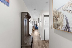 A hallway with a wooden bench, a white door, and a framed picture on the wall. - Steps to Beach, Pool and Hot Tub, Near Pier Park | Endless Summer D8 (Panama City Beach)