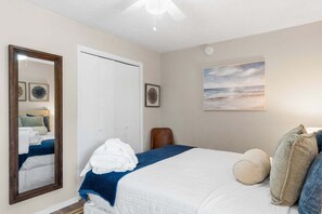 A hotel room with a bed, a large mirror, a door, and a painting on the wall. - Steps to Beach, Pool and Hot Tub, Near Pier Park | Endless Summer D8 (Panama City Beach)