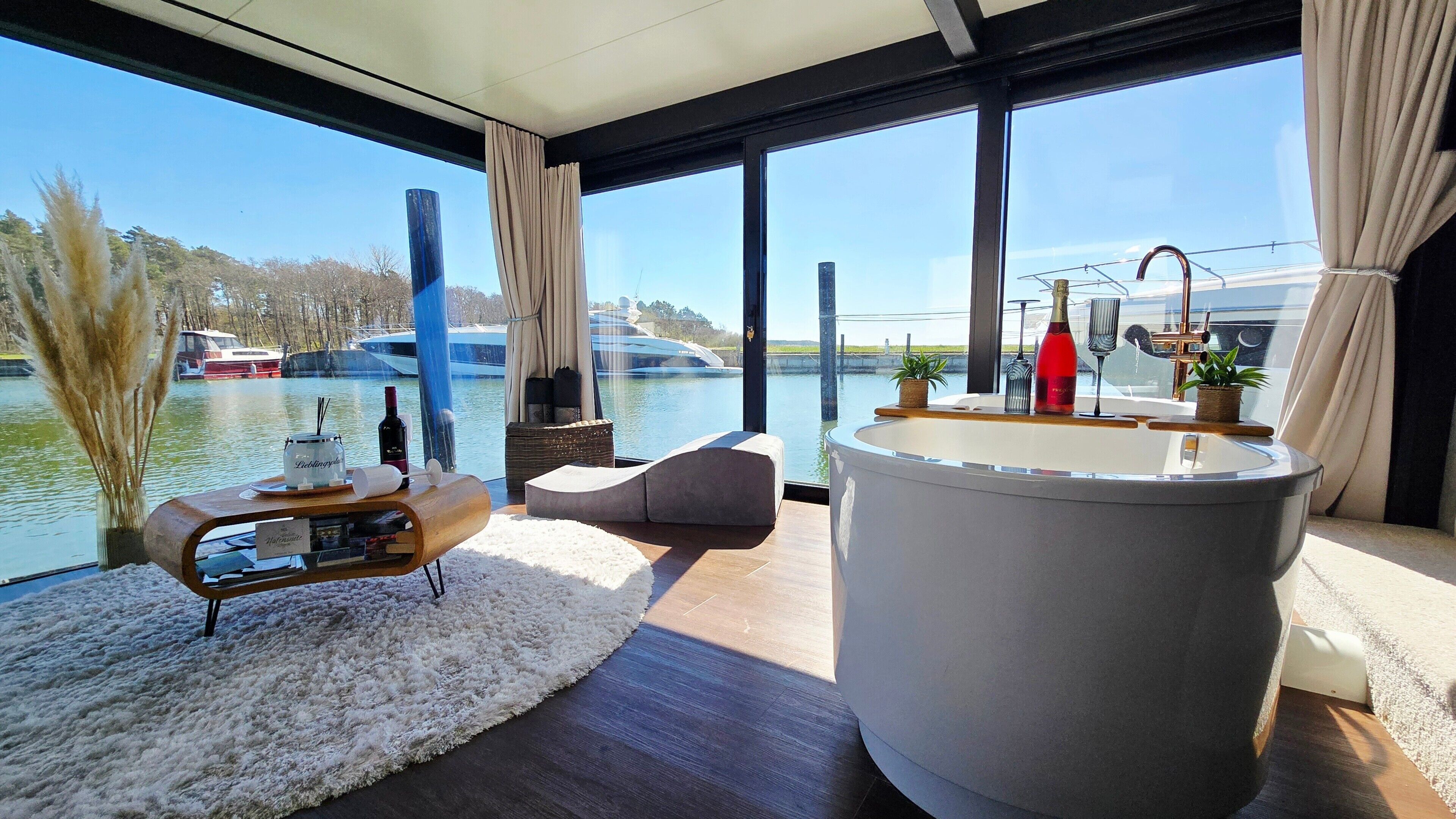 A modern interior with a large window overlooking a body of water, a seating area, and a bar.