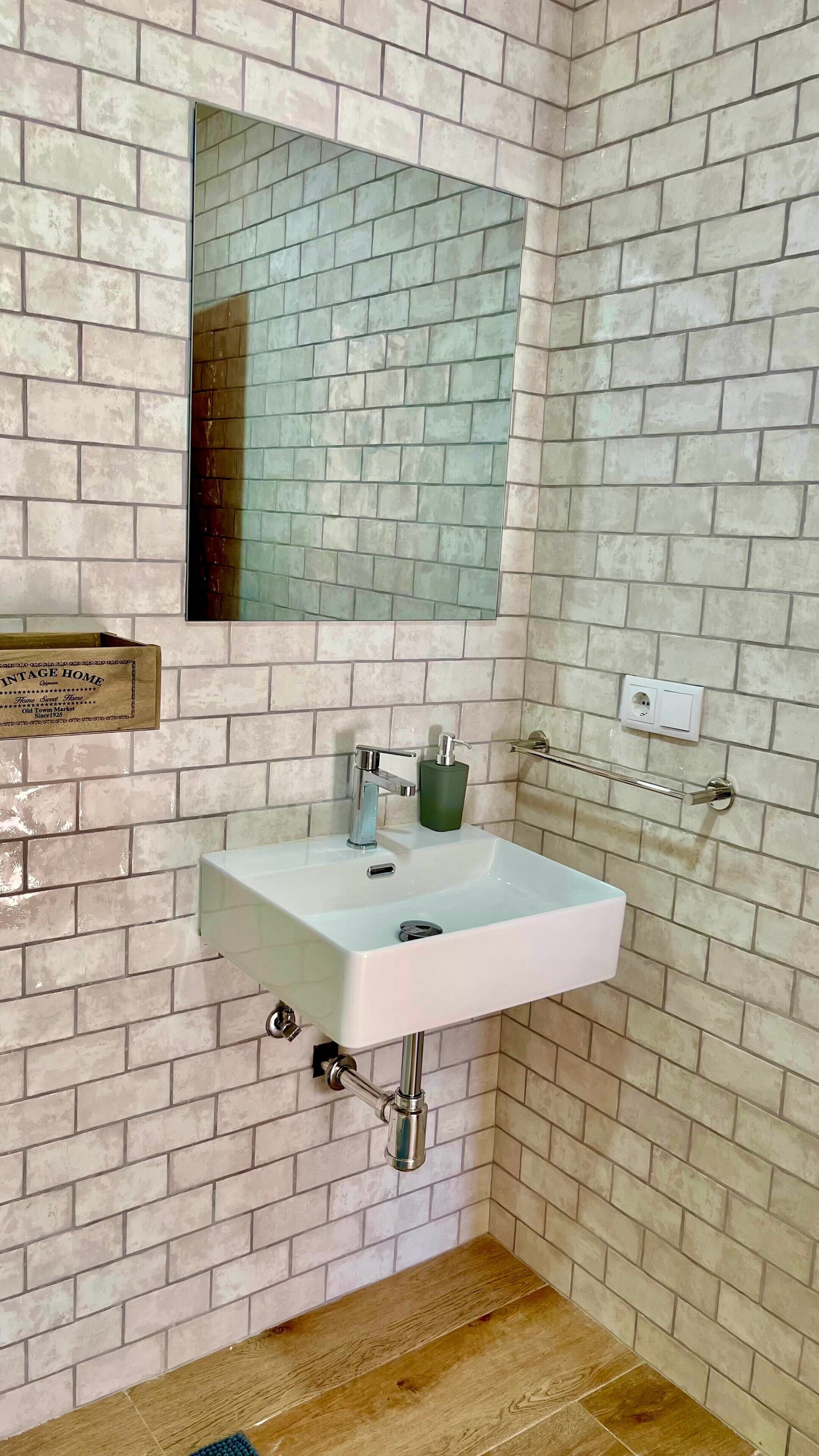 Un baño con un lavamanos blanco, un espejo y un dispensador de jabón verde.