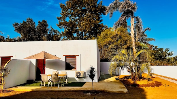 A modern building with a patio area, outdoor seating, and a palm tree. - Casa Golondrinas Verdes, Cartaya – Private Garden, Beach & Pets Welcome (Cartaya)