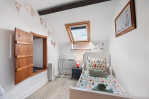 A child's bedroom with a bunk bed, a desk, a chair, a radiator, and a window with a view of the sky. - Hill crest farmhouse (Vengeons)
