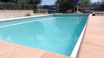 Una piscina rectangular con borde de azulejos, rodeada de una terraza de piedra.
