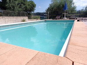 A rectangular swimming pool with a tiled edge, surrounded by a stone deck.