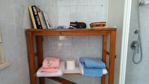 A bathroom with a wooden shelf holding towels, toilet paper, and a small basket. - Villa 'La Panchina' with private pool, Wi-Fi, and air conditioning (Noto)