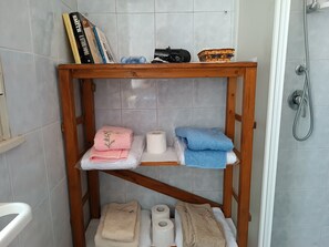 Ein Badezimmer mit einer Holzwand, auf der Handtücher, Toilettenpapier und ein kleiner Korb liegen.
