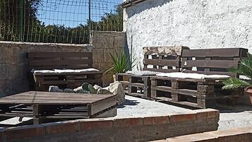 Un espace extérieur aménagé avec des meubles en bois, une plante en pot et un mur en pierre.