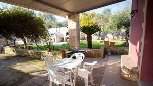An outdoor patio with a table and chairs, surrounded by stone walls and potted plants. - Villa 'La Panchina' with private pool, Wi-Fi, and air conditioning (Noto)